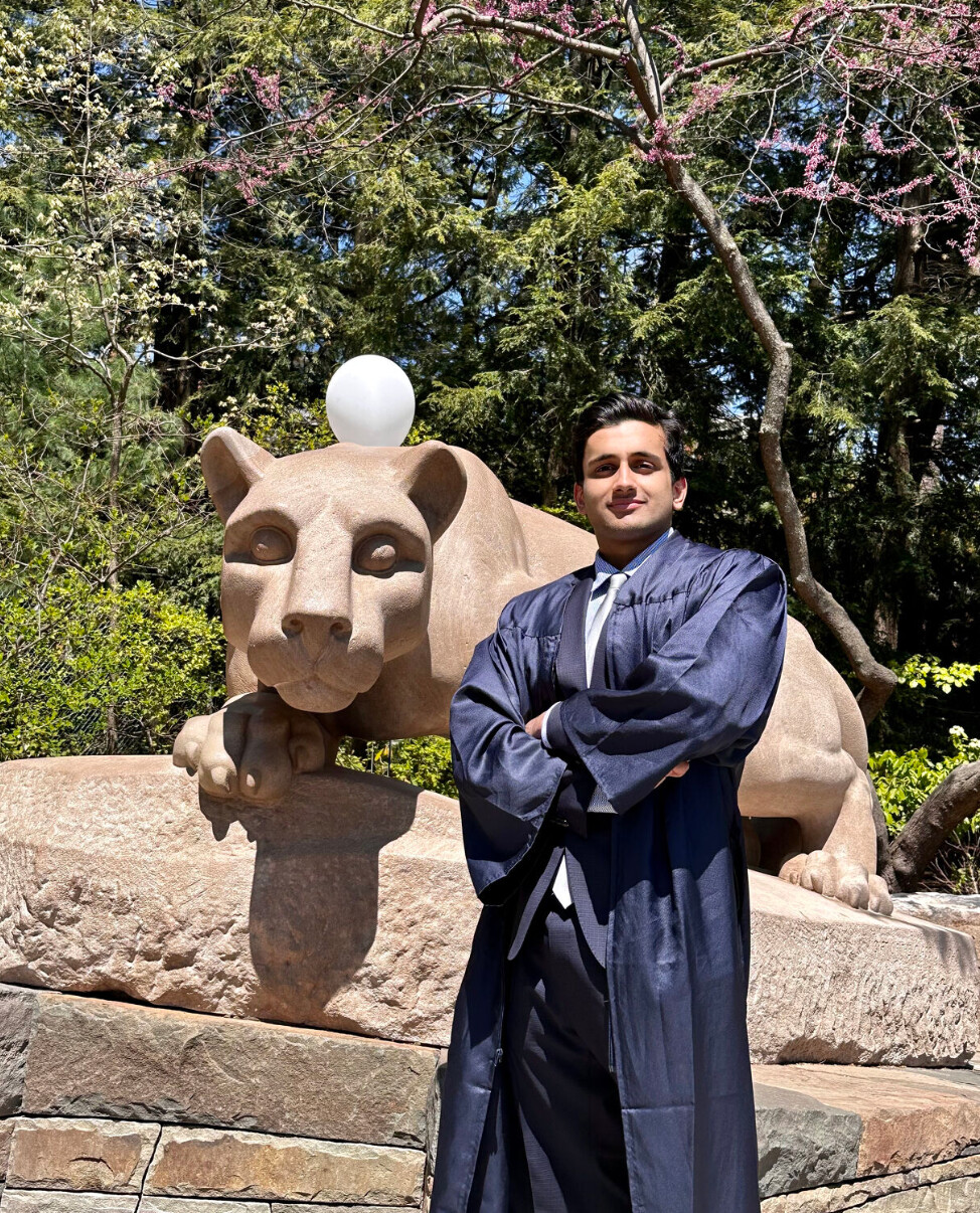 Shubham Mishra in graduation attire beside the Penn State Nittany Lion Shrine
